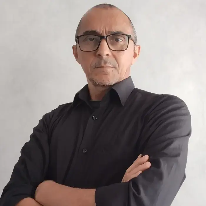 Riceles Costa fazendo uma pose com os braços cruzados usando uma camisa preta.